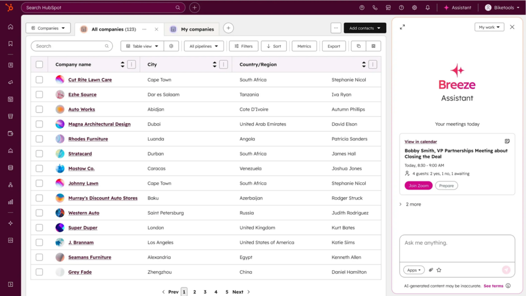 A computer screen displays a CRM dashboard with a list of companies, their cities, regions, and associated contacts. On the right, a sidebar shows a chat with the Breeze Assistant AI Copilot for Support Teams about scheduling a meeting.